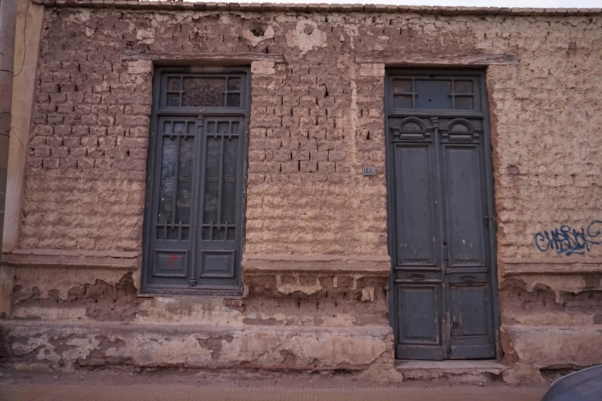 Dos puertas de madera cerradas en una fachada antigua de ladrillo